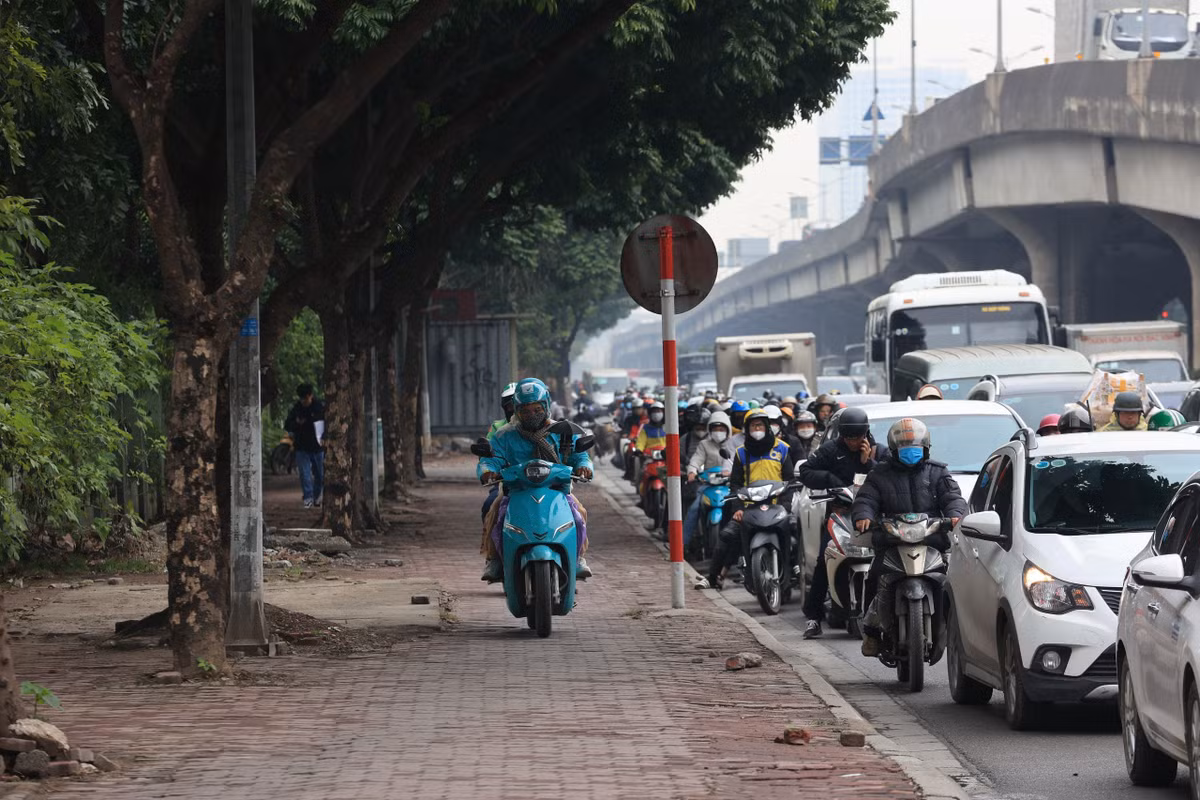 Lòng đường chật kín xe buộc những phương tiện xe máy phải leo lên vỉa hè để di chuyển.