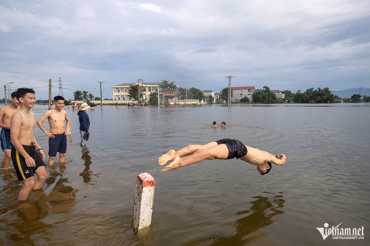 Những ngày này, thanh niên làng được dịp bơi lội ngay trên cánh đồng ngập nước. Ảnh: Phạm Quốc Dũng