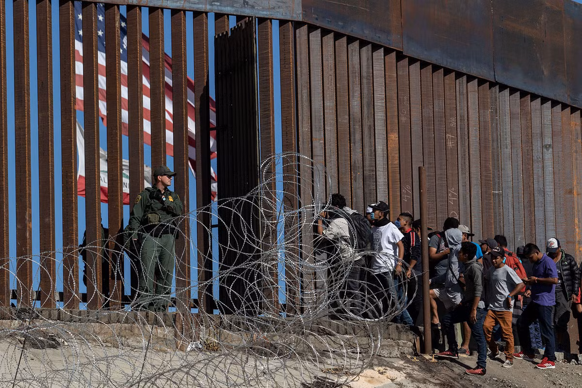 Lính Mỹ đứng cạnh bức tường giữa biên giới nước này với Mexico trong khi đang có rất nhiều người muốn vượt biên vào đất Mỹ. Nguồn ảnh: Theatlantics.