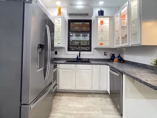 Nhà bếp có bồn rửa đôi, lò nướng, máy rửa bát, vòi nước, lò vi sóng và tủ lạnh.