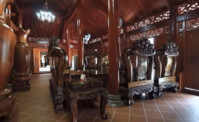 Tại gian chính của ngôi nhà, gia chủ bày bộ bàn ghế "khổng lồ" làm từ gỗ cẩm Việt - một loại gỗ giá trị cao, có hương thơm đặc trưng, vân đẹp. Ảnh chụp màn hình NhaTo