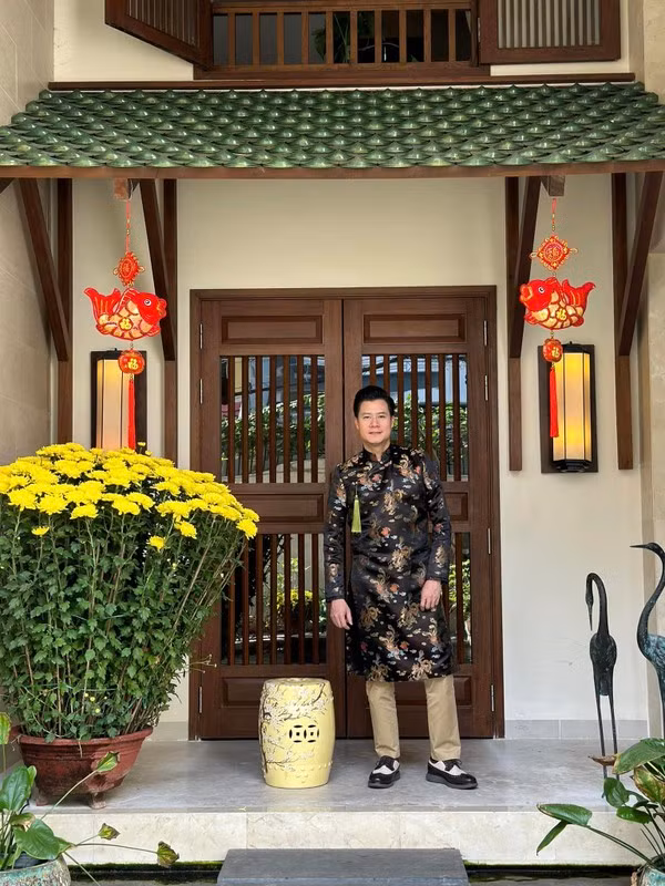 Không gian xung quanh căn nhà có nhiều cây xanh, hồ nước, đèn lồng và đồ gỗ.