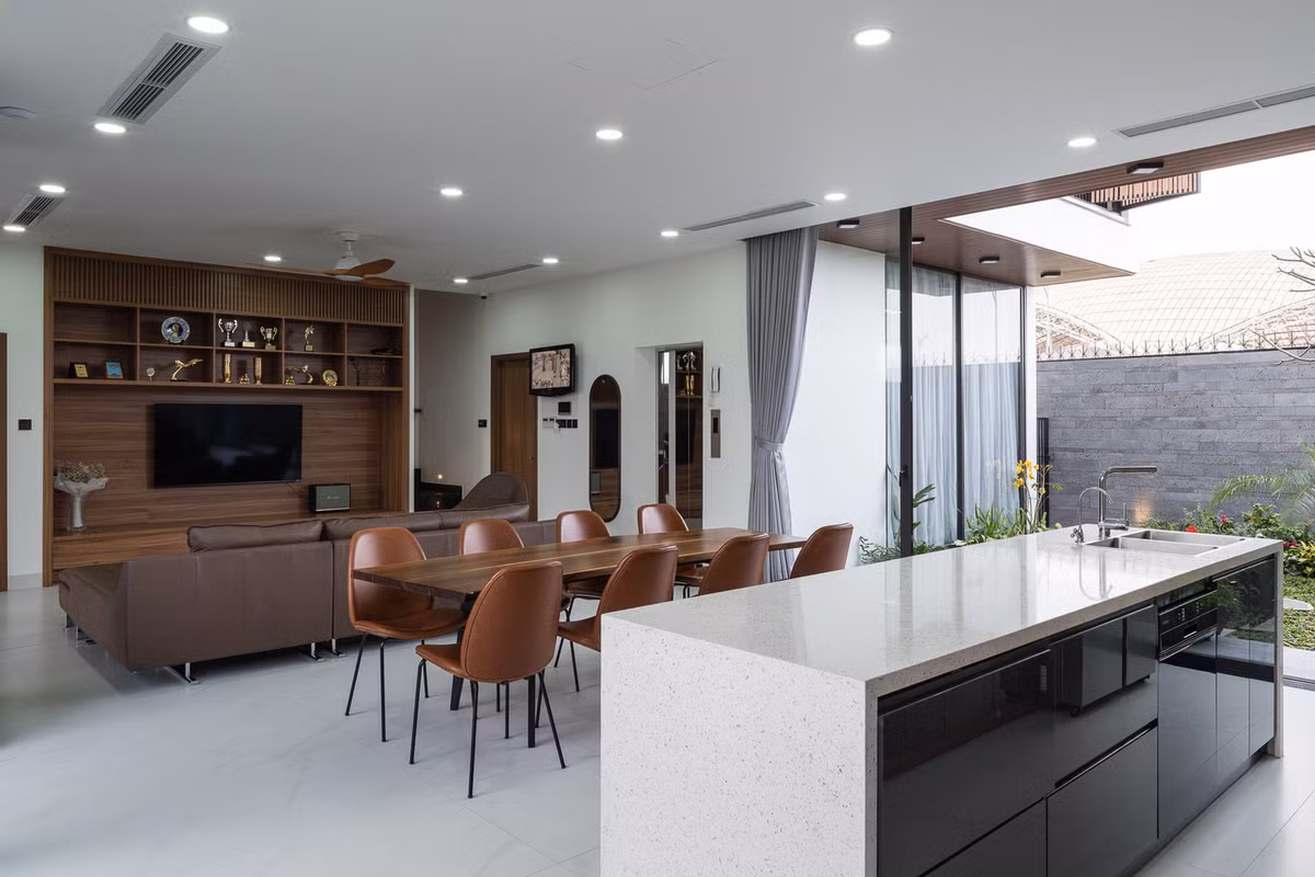 Khu bếp mở nối sân trước và sân sau để mở rộng không gian. Nội thất lấy tông màu nâu gỗ làm chủ đạo, bàn ghế ăn được bố trí giữa đảo bếp và không gian tiếp khách.