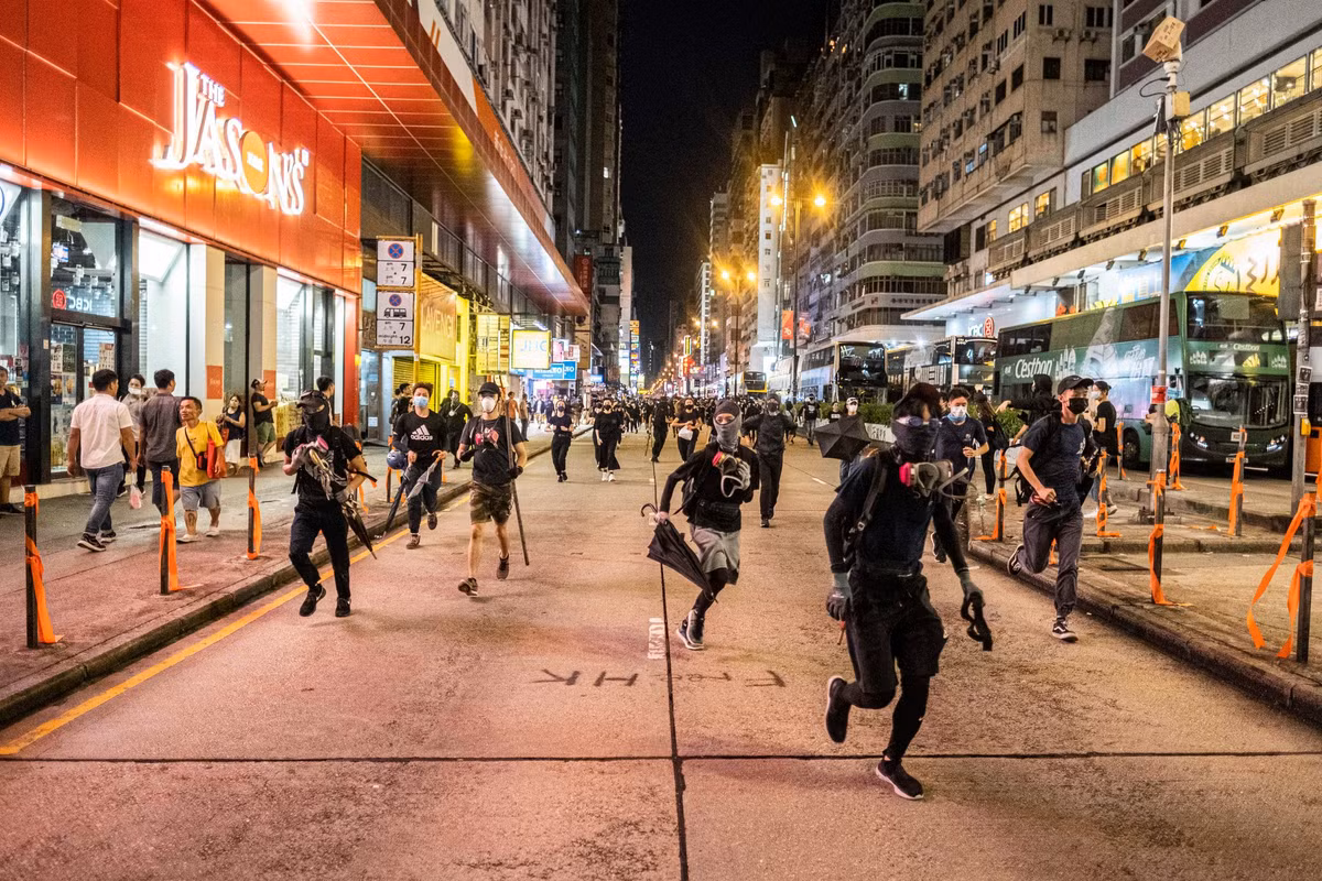 Một số người biểu tình đeo mặt nạ tháo chạy trên đường phố Mong Kok.