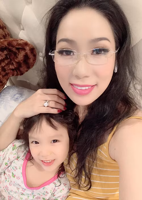 Trịnh Kim Chi đeo kính đọc truyện cho con gái trước khi đi ngủ.