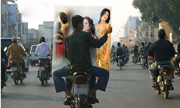 Dường như bức ảnh trong tấm biển quảng cáo "ngỡ ngàng" khi thấy người đàn ông ngồi sau xe máy đặt tay lên vai.