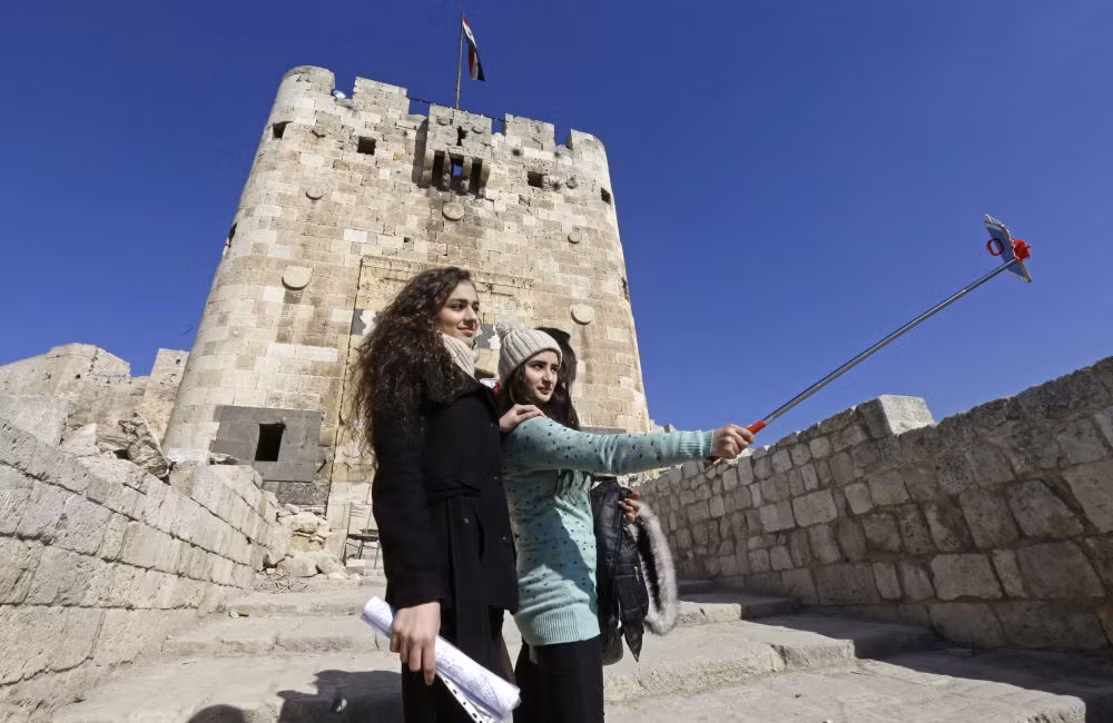 Hai cô gái Syria chụp ảnh "tự sướng" bên ngoài Thành cổ Aleppo. Ảnh Sputnik
