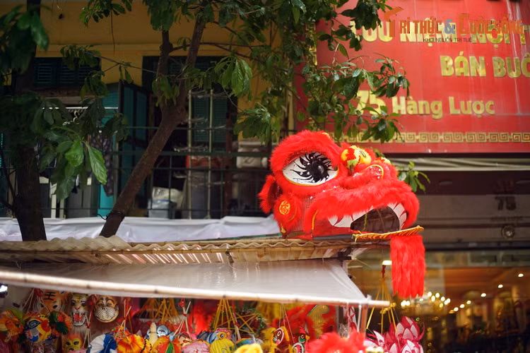 Chiếc đầu lân đỏ rực "ngắm" dòng người qua lại từ mái che của một gian hàng trên phố Hàng Lược.