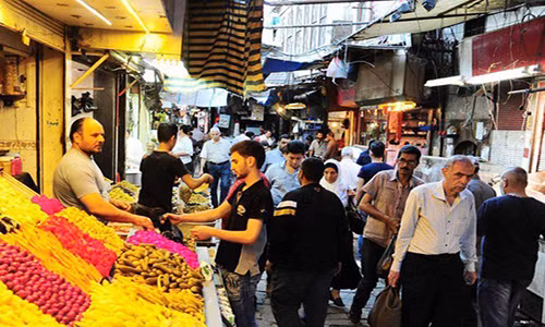 Người dân đi qua những quầy hàng tại một khu chợ ở thủ đô Damascus. Ảnh: FNA.