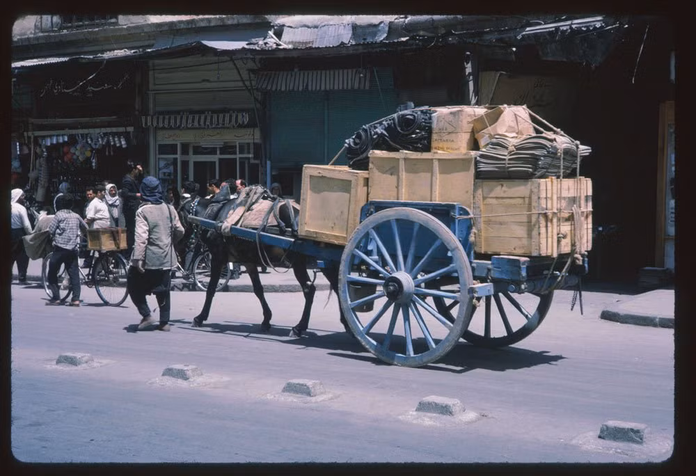 Một cỗ xe ngựa chở nhiều hàng hóa di chuyển trên đường phố Damascus.