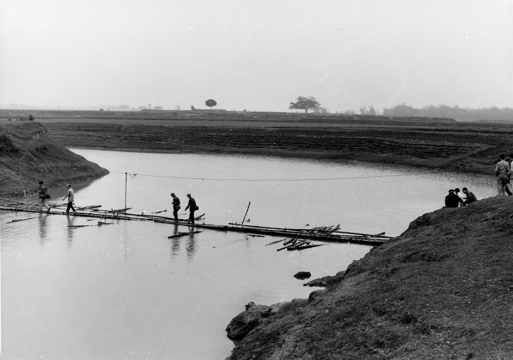 Người dân đi qua sông trên cầu tạm ghép bằng tre.