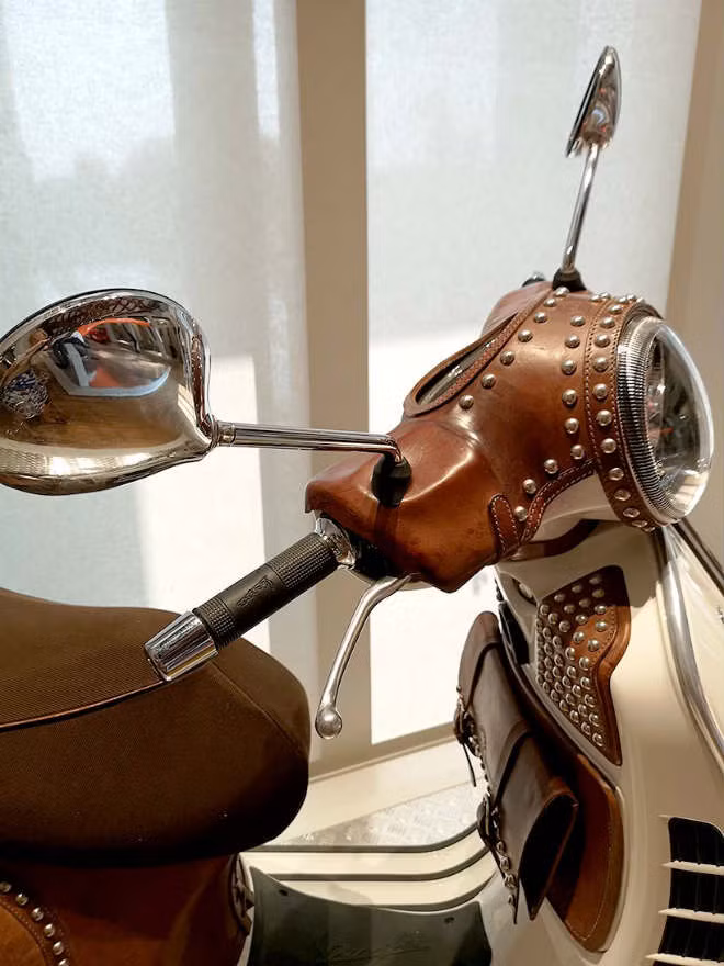 Những siêu phẩm Vespa bọc da này do hãng Bottega Conticelli sáng tạo nên. Tất cả các thao tác bọc da lên xe Vespa đều được tiến hành thủ công. Các tấm da được uống cầu kì, kết nối bằng loại chất sáp tạo độ chống nước rất tốt.