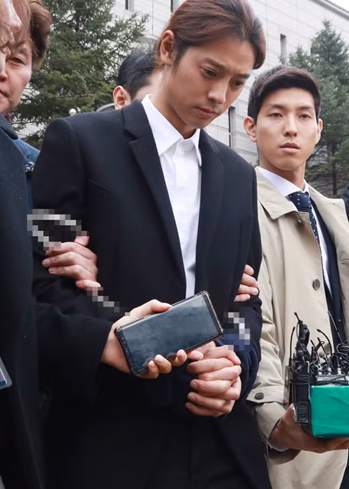 Jung Joon Young liên tục cúi đầu khi bị áp giải đến đồn cảnh sát gần nhất trong khi cảnh sát chờ lệnh bắt giữ chính thức từ tòa án. Ảnh: Chosun
