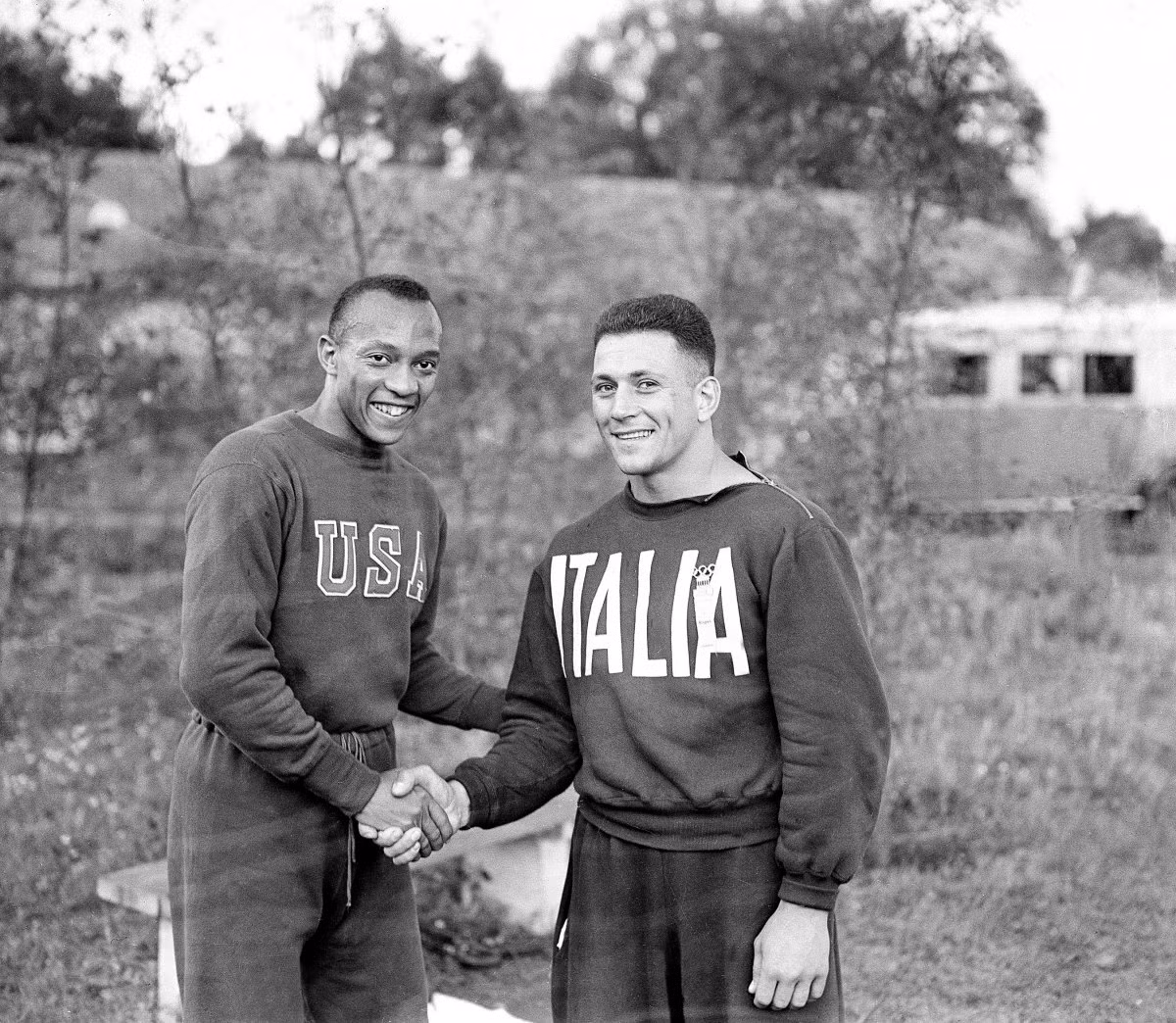 Trong ảnh là vận động viên người Mỹ Jesse Owens bắt tay thiện chí với vận động viên đối thủ người Italy tại Làng Olympic năm 1936. Khoảng 4.000 vận động viên đến từ những đội thể thao mạnh trên thế giới.