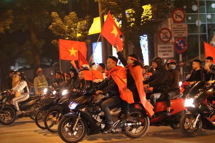 Tuy nhiên, trong dòng người đổ ra đường diễu hành chia vui chiến thắng, có một bộ phận CĐV không đội mũ bảo hiểm. (Ảnh Infonet)