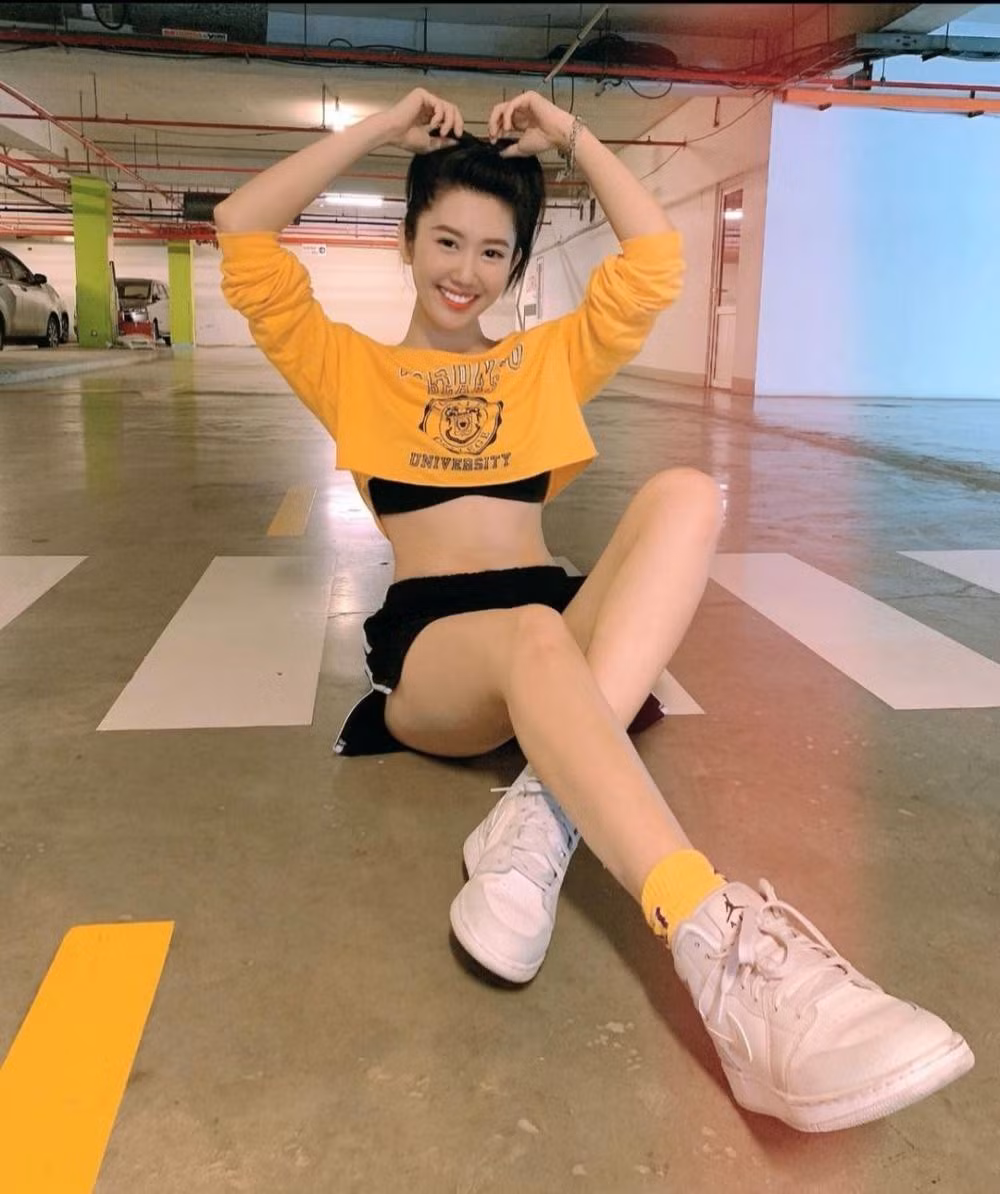 Thúy Ngân trẻ trung, năng động với set đồ tập màu đen: Áo crop-top tay dài màu vàng nổi bật, đi giày sneaker và tất cùng màu với áo.