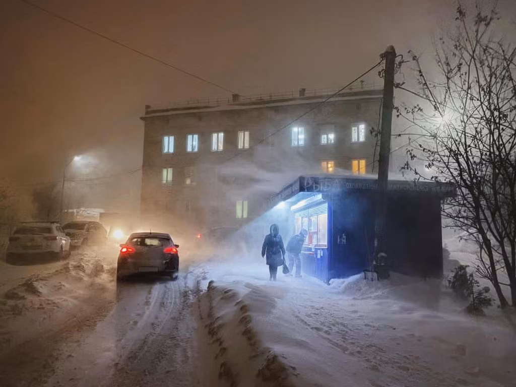 Một khách hàng nhìn vào trong tiệm bán cá giữa trận bão tuyết ở Murmansk.