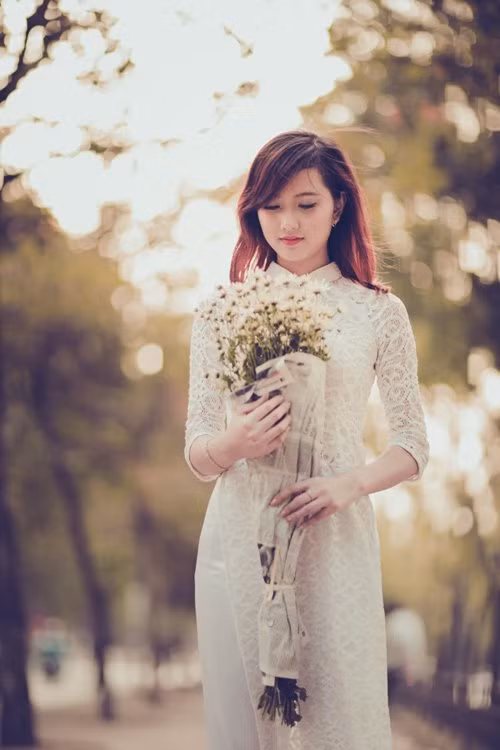Hình ảnh cô gái ôm bó cúc họa mi bước đi giữa phố Hà Nội đẹp như một bức tranh.