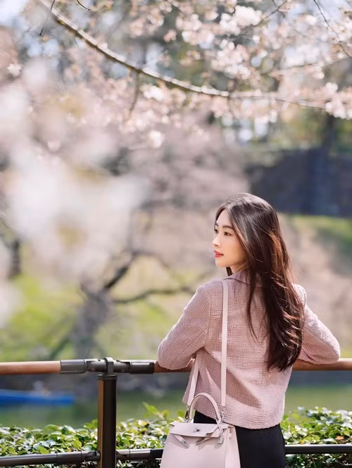 Bà mẹ hai con diện áo khoác gam hồng pastel và sử dụng túi xách cùng tông màu.