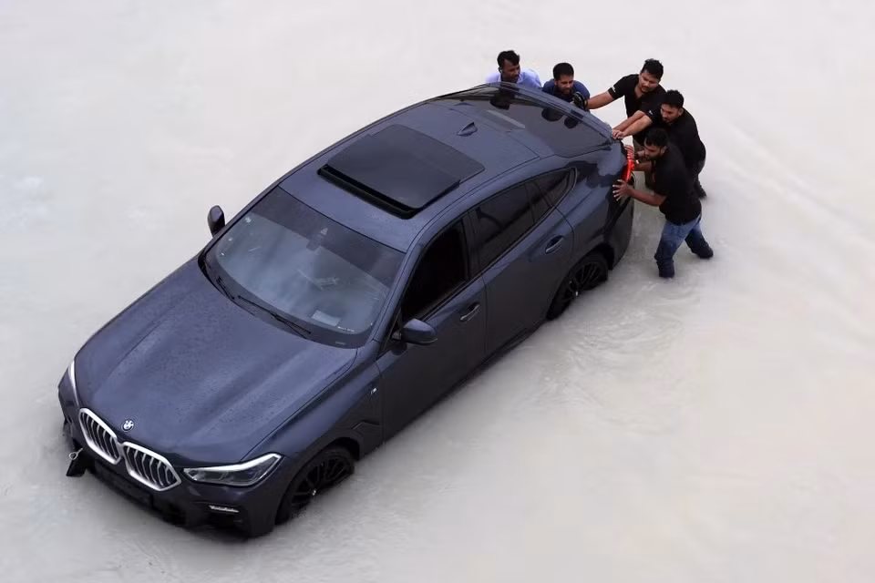 Người dân Dubai hì hục đẩy một chiếc BMW X6 khác. Chia sẻ nhiều công nghệ với X5, BMW X6 mang phong cách thể thao coupe đặc trưng.