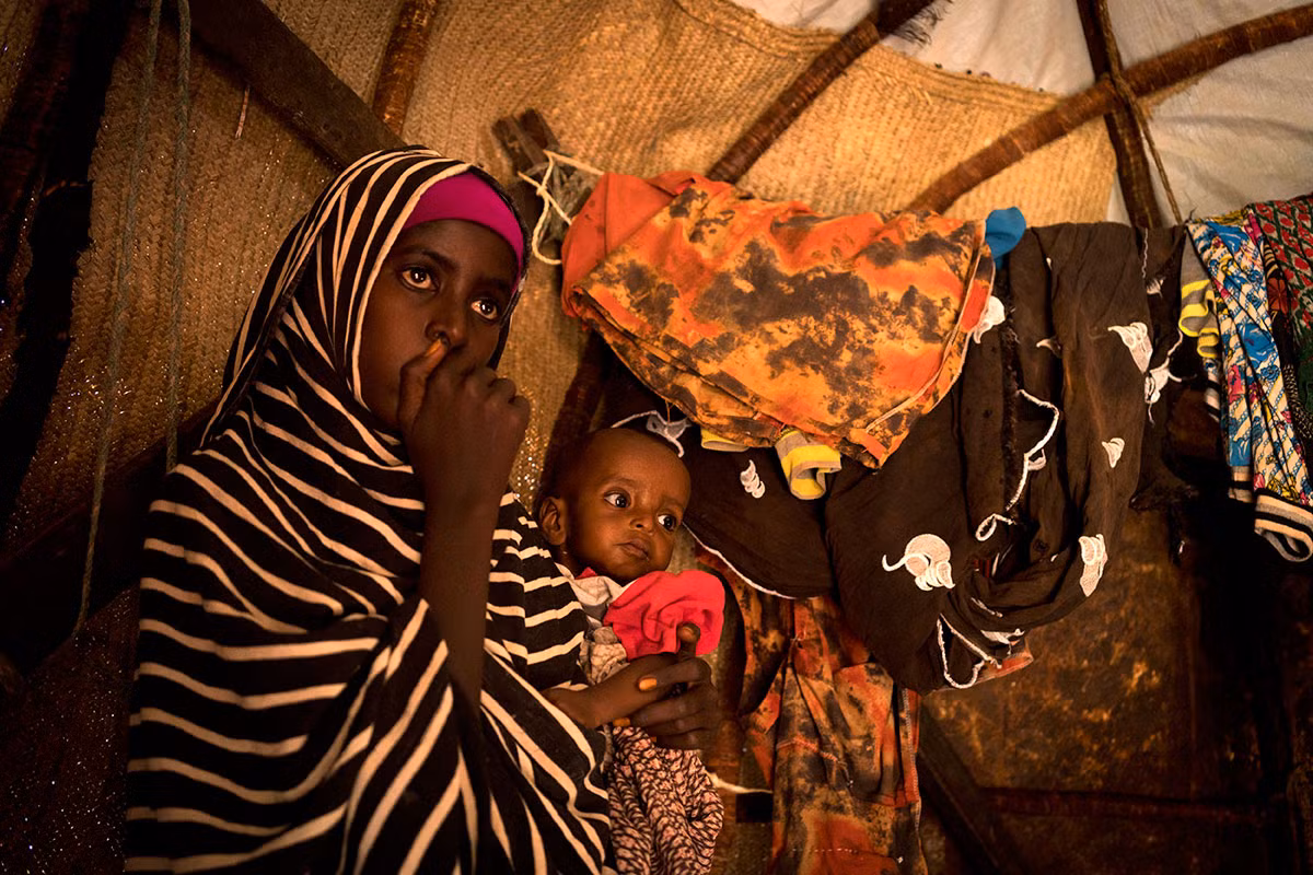 Fatumo, 12 tuổi, đang bế em trai của mình tại Uusgure, Puntland. Được biết, em trai của Fatumo đã bị sốt trong suốt hai tháng qua.