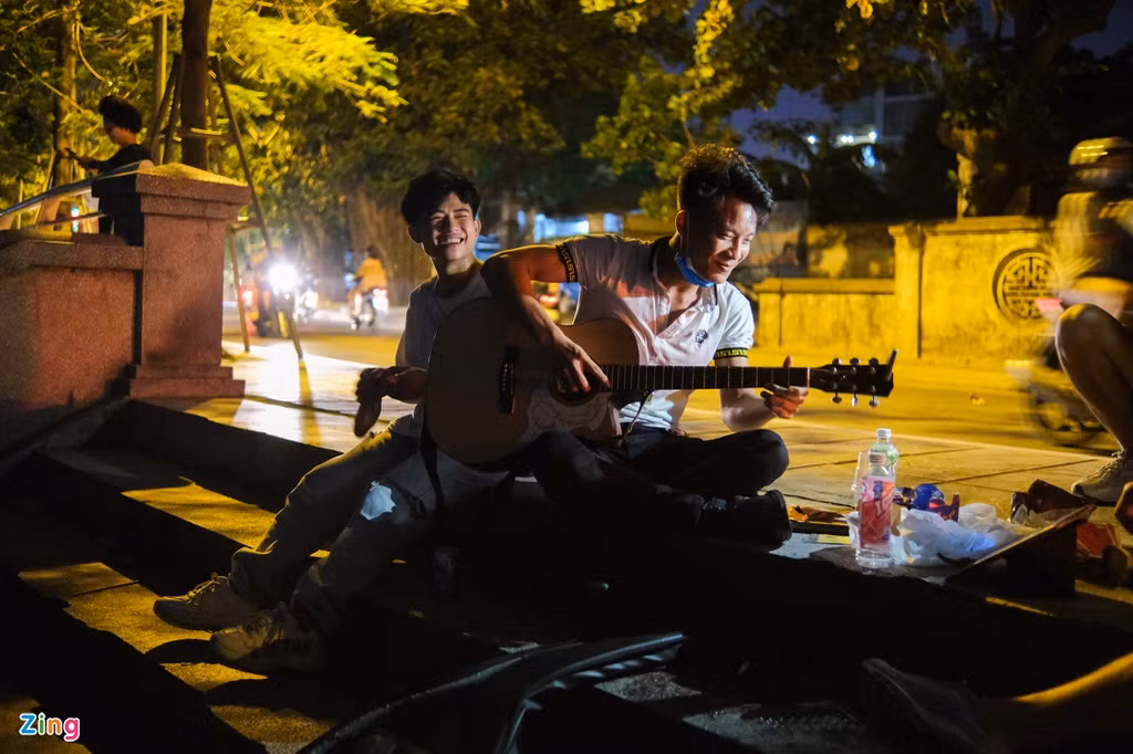 Tại bậc cầu thang dẫn xuống hồ Tây ở đoạn phố Vệ Hồ, một nhóm 4 nam thanh niên trẻ tuổi cùng nhau ngồi đàn hát và đón những cơn gió nóng mùa hè thổi từ phía mặt nước.