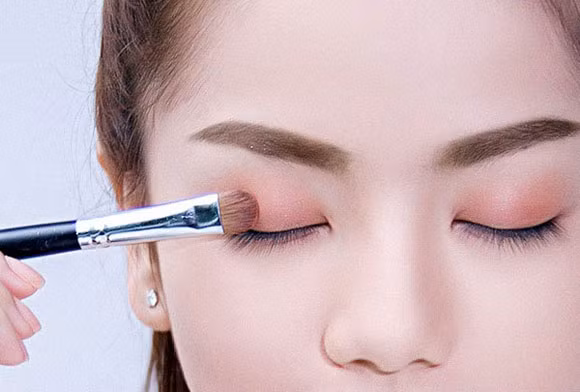 Đánh mắt gam hồng nude đáng yêu. Phủ lên toàn bộ bầu mắt trên một gam màu cam nhạt. Đánh nhấn 1/3 cho bầu mắt trên sát chân mi với gam nâu đồng.