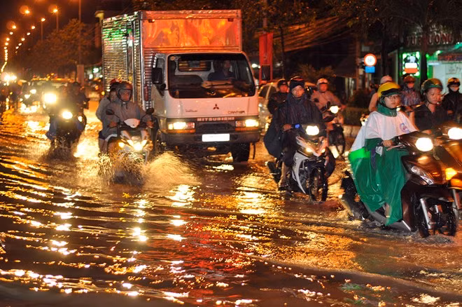 Người tham gia giao thông điều khiển phương tiện, dò dẫm đi trên con đường ngập nước.