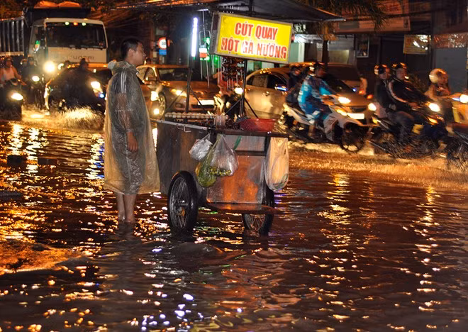 Một người bán hàng rong trên vỉa hè đường Đồng Khởi bị nước "bao vây".