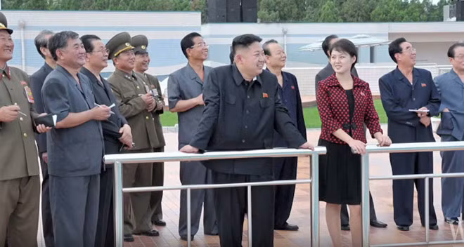 Phu nhân Ri Sol Ju diện váy đen cùng mẫu áo khoác chấm bi sắc đỏ trong chuyến thăm công viên giải trí.
