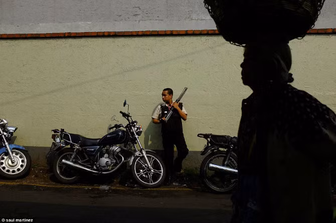 Nhân viên an ninh Guatemala mang theo súng đứng gác ở một khu chợ trong thành phố.