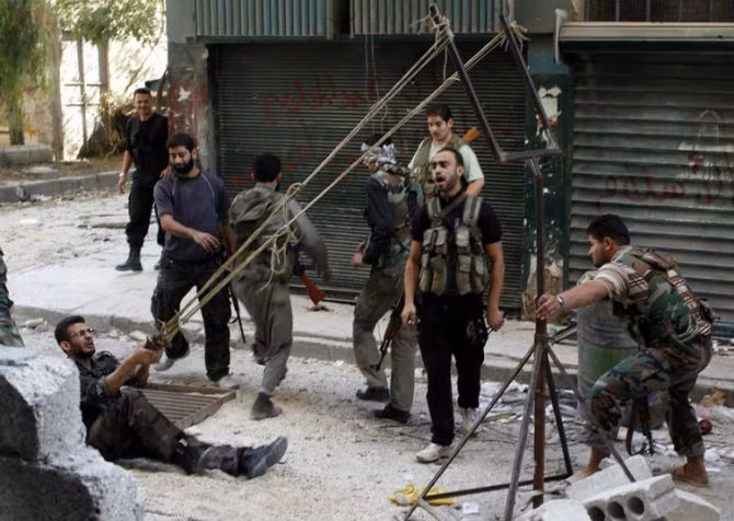 Các chiến binh nổi dậy sử dụng súng cao su nã lựu đạn tự chế vào binh sĩ chính phủ Syria tại thành phố Aleppo.