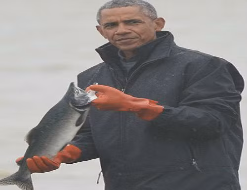Ông Obama cầm một con cá hồi trên tay.