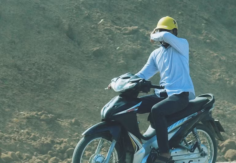 Nam thanh niên cố gắng dùng một tay để bịt kín mặt khi di chuyển qua con đường bão bụi.