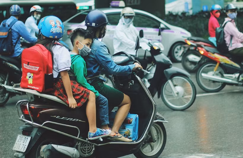 Nhiều em nhỏ được phụ huynh mặc thêm áo khoác khi di chuyển đến từ trên xe máy để đến trường học.