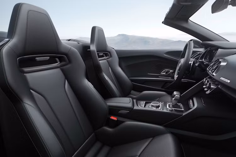 Các chi tiết thiết kế còn lại của R8 Spyder, bao gồm cả nội thất hoàn toàn giống như R8 Coupe. Xe có bảng điều khiển tối giản, bảng đồng hồ kỹ thuật số Virtual Cockpit và những chiếc ghế bọc da chần chỉ vân con thoi sang trọng. Đương nhiên, với bộ mui xếp mới, R8 Spyder sẽ có thêm một nút bấm đóng mở mui trên bệ điều khiển trung tâm bằng sợi carbon.