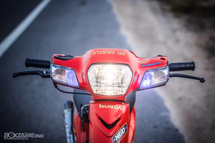 Thuộc sở hữu của một biker Thái Lan, chiếc Dream Super Cub 110 đã có kiểu dáng không thay đổi quá nhiều so với nguyên bản, nhưng vẫn đầy nổi bật bởi các chi tiết độ kiểng. Ở phía trước, phần đầu của chiếc xe được giữ nguyên, chỉ chế lại cặp đèn demi LED xanh nổi bật hơn và cùm phanh Brembo.