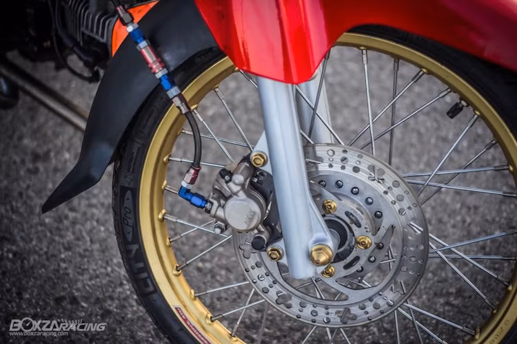 Vốn được trang bị phanh đùm nguyên bản, chiếc Dream Super Cub đã được chủ xe nâng cấp lên hệ thống phanh đĩa trước với heo Nissin và đĩa từ Honda Wave RSX được phay lại, kết hợp với dây dầu Earl's. Theo phong cách xe đua drag, chiếc xe cũng được độ cặp niềng nhôm bản mỏng với màu vàng nổi bật.
