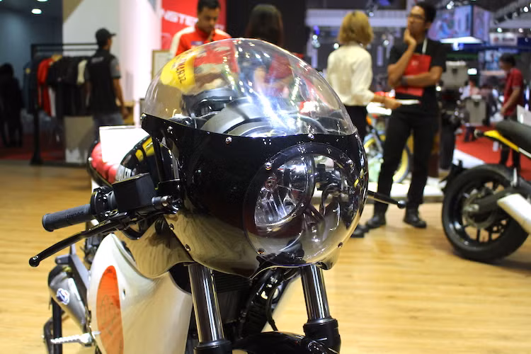 Trên bản độ này, Sang Thanh Đa đã chế cho chiếc Scrambler Sixty2 một bộ quây gió tròn đầy tính khí động học, chắn toàn bộ cụm đèn pha nguyên bản của chiếc xe. Có vẻ đẹp đơn giản, tuy nhiên chế tạo bộ quây này là một thử thách không nhỏ khi xưởng độ phải uốn cong các tấm mica theo kiểu dáng mong muốn, nhưng vẫn phải đảm bảo độ trong.