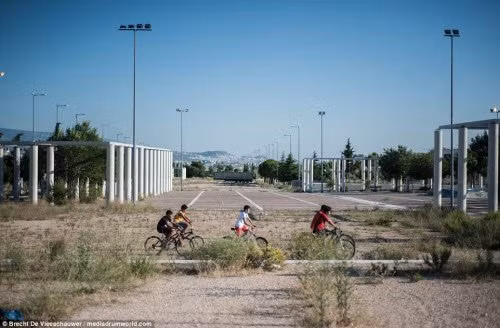 Trẻ em đạp xe trong khuôn viên hoang tàn của làng Olympic được xây dựng để phục vụ cho 10.000 người ở trong thời gian Olympic 2004 diễn ra.