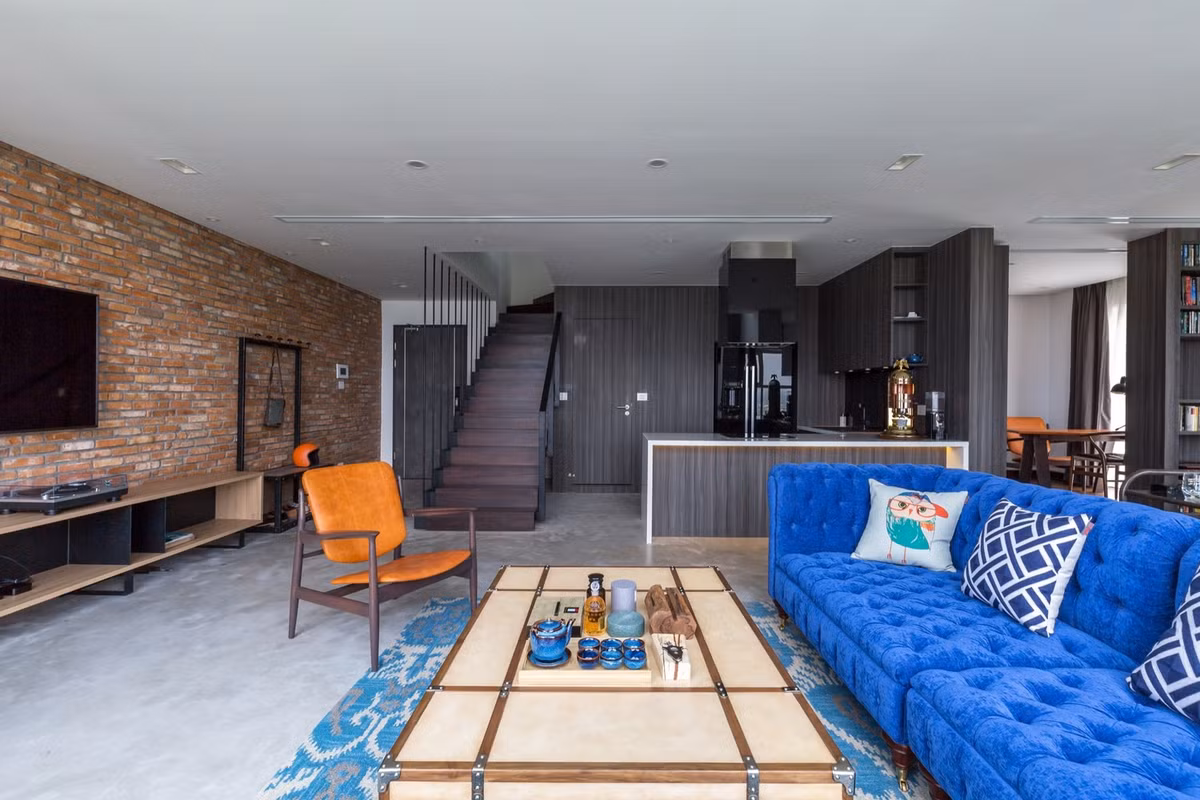 Phòng khách của căn hộ nổi bật với ghế sofa xanh giữa nền tường màu tối.