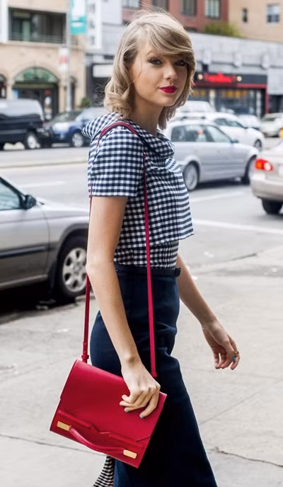 Chiếc túi cầm tay Midi màu đỏ hồng của J.Mendel được Taylor Swift sử dụng không chỉ ngoài đường phố mà cả khi tham dự sự kiện. Giá của nó là 1.650 USD (hơn 36 triệu đồng).