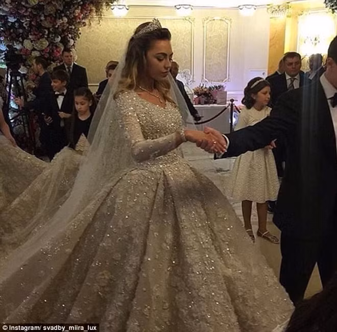 Cô dâu Uzhakhova khoác trên người chiếc váy cưới hiệu Elie Saab nhập khẩu từ Paris, trị giá khoảng 18.000 bảng Anh (tương đương 555 triệu đồng). Chiếc váy nặng hơn 11 kg, cần đến vài người giúp nâng váy lúc bước lên cầu thang.