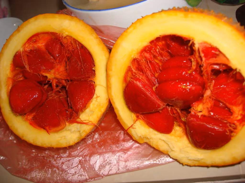 Cách làm mứt gấc đơn giản tại nhà. Bước 1: Bổ đôi quả gấc chín lấy phần hạt gấc tách phần màng rồi bỏ hạt.