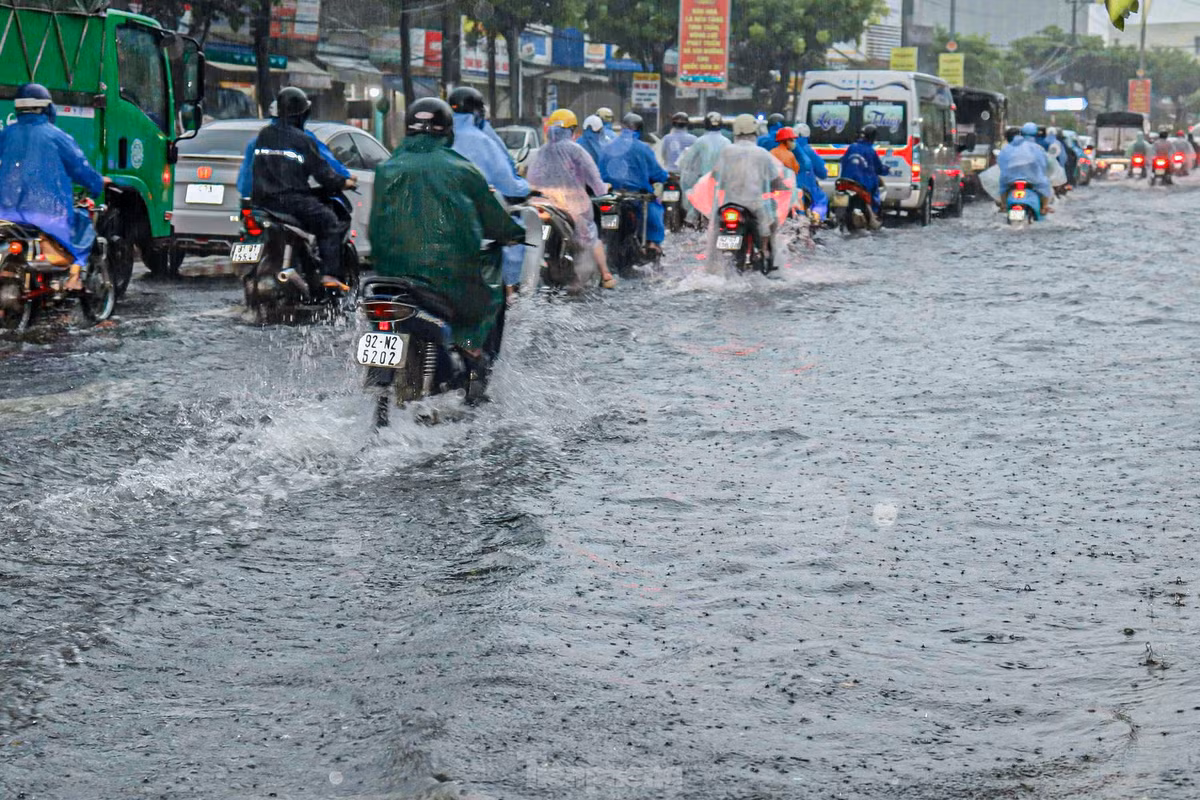 Dòng người vội vã đi làm dưới trời mưa lớn, xe cộ ùn tắc do nước ngập.