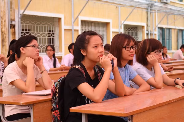 Các tân sinh viên ngồi chờ đến khoa mình vào đăng kí.