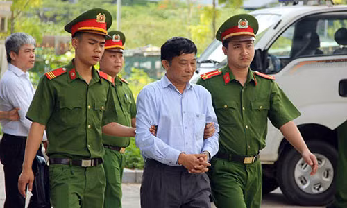 Bị cáo Ninh Văn Quỳnh (đi trước) và bị cáo Nguyễn Xuân Sơn (sau) được cảnh sát dẫn giải đến tòa.