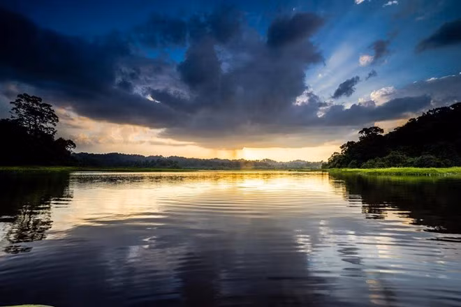 Hoàng hôn trên Bàu Sấu. Ánh mặt trời hừng lên từ đám mây đen ở rặng núi phía xa.
