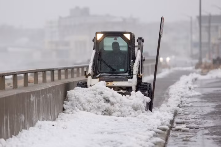 Một công nhân lái xe dọn tuyết trên con đường dọc Bãi biển Nantasket ở Hull, Massachusette.