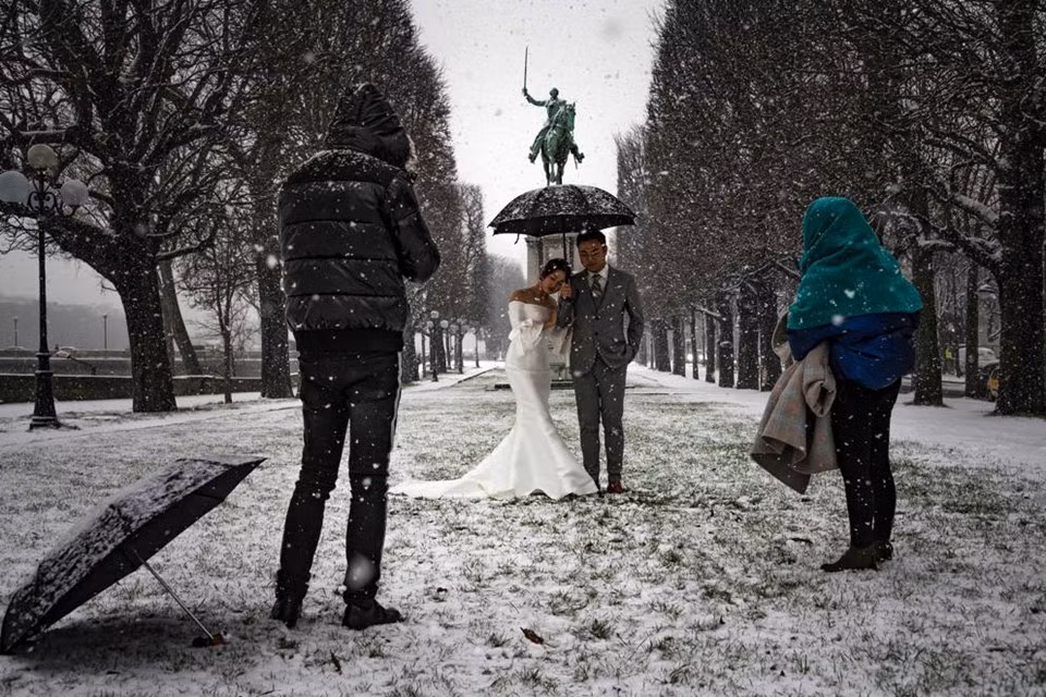 Một cặp vợ chồng tạo dáng chụp ảnh giữa trời tuyết ở Paris. Công viên phủ đầy tuyết gần sông Seine ở Paris mang đến bối cảnh ấn tượng và lãng mạn cho bộ ảnh của cặp đôi mới cưới này.